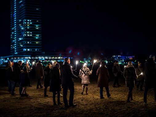 Personen am Strand mit Fackeln während der Fackelwanderung in Travemünde